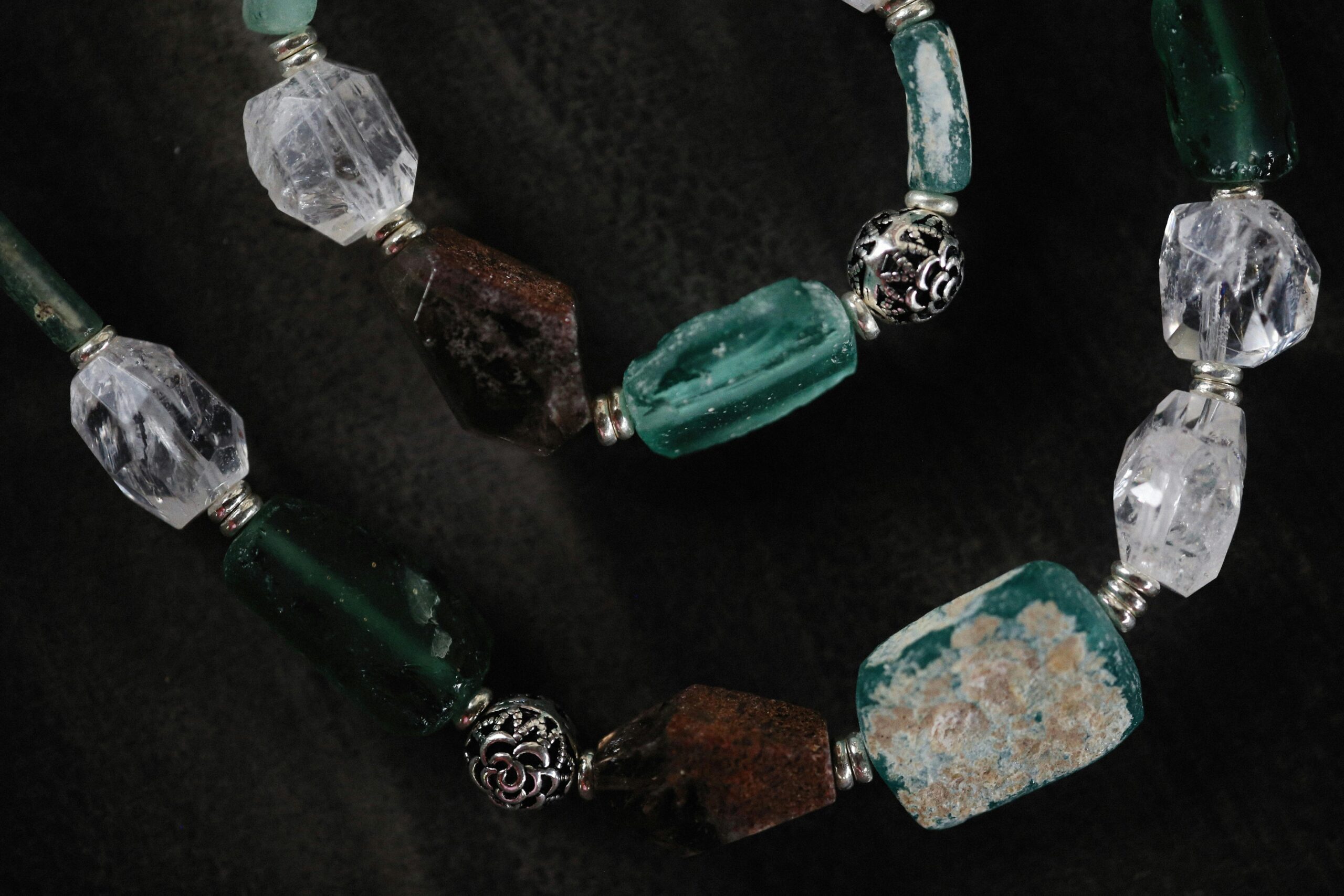 Products Close-up of a beaded necklace featuring various gemstones and intricate metalwork.