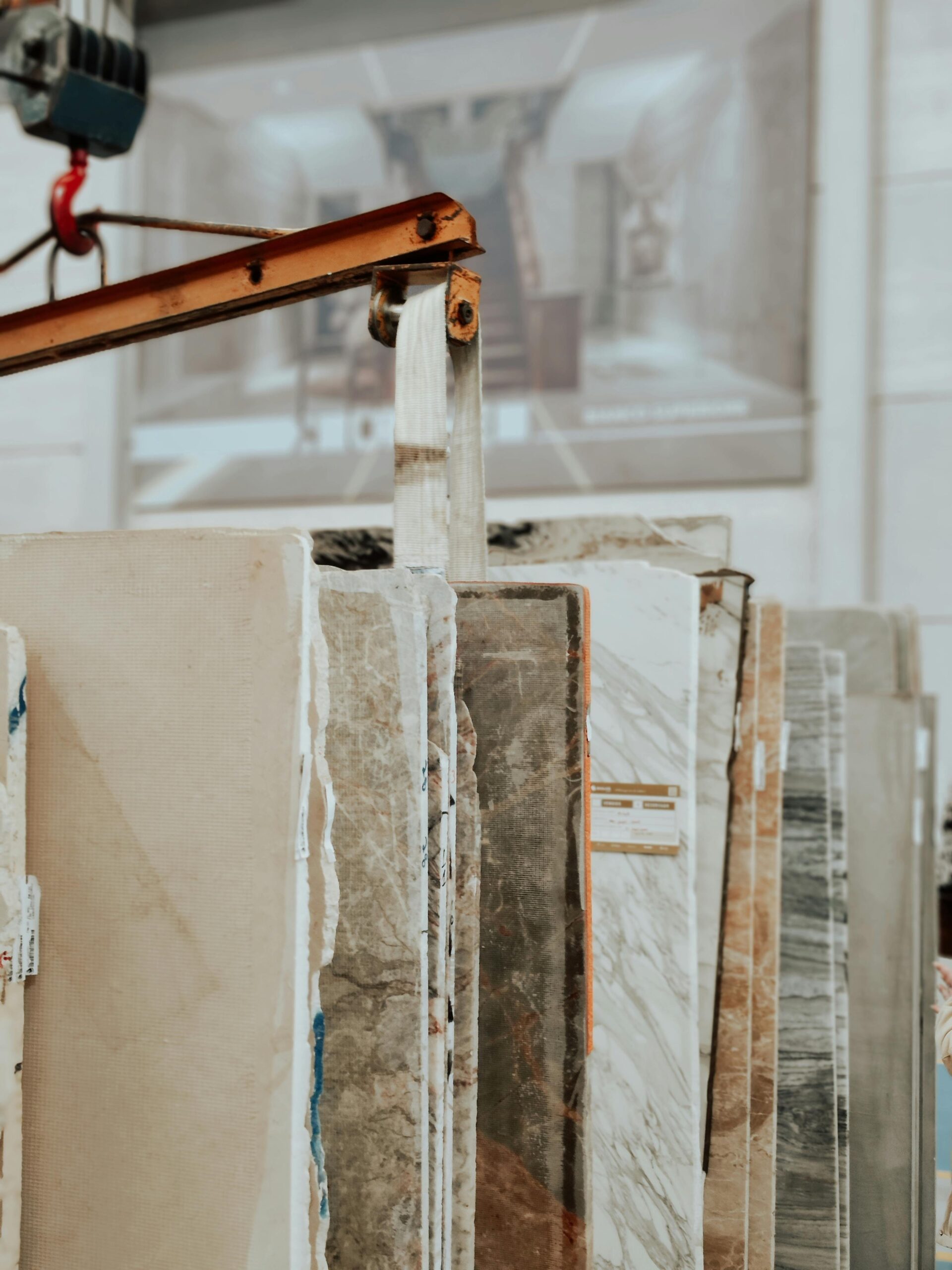 Products Vertical shot of marble and granite slabs with a construction hook indoors.