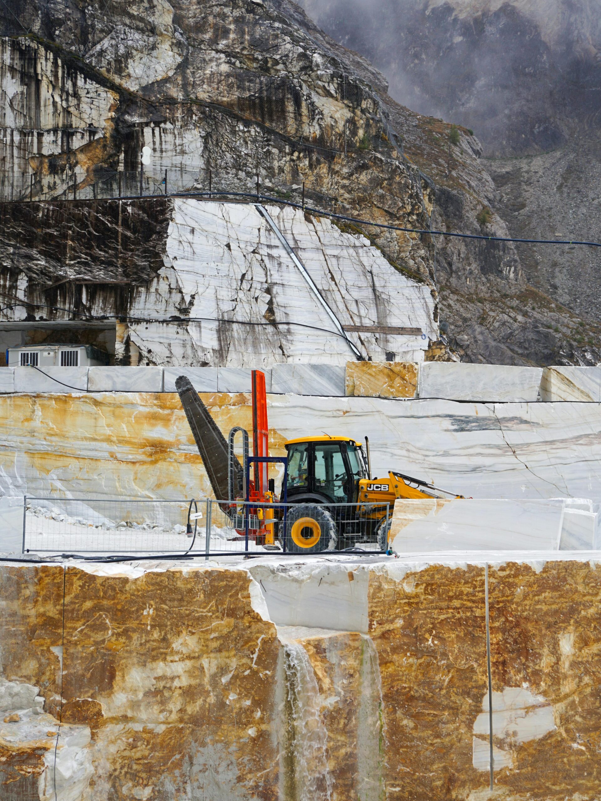 Products Heavy machinery in the iconic marble quarry of Carrara, Italy, showcasing raw material extraction.