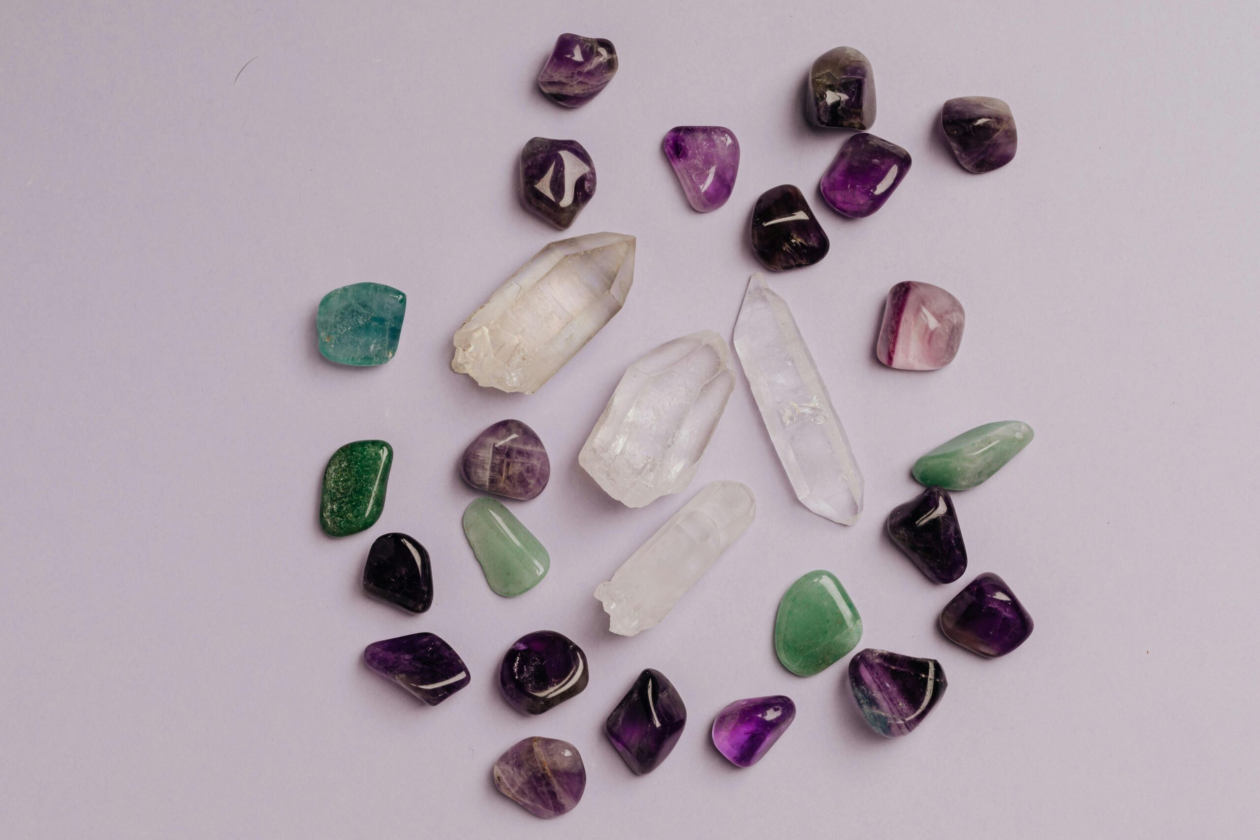 Products A collection of assorted gemstones including amethyst, jade, and quartz arranged in a flat lay.