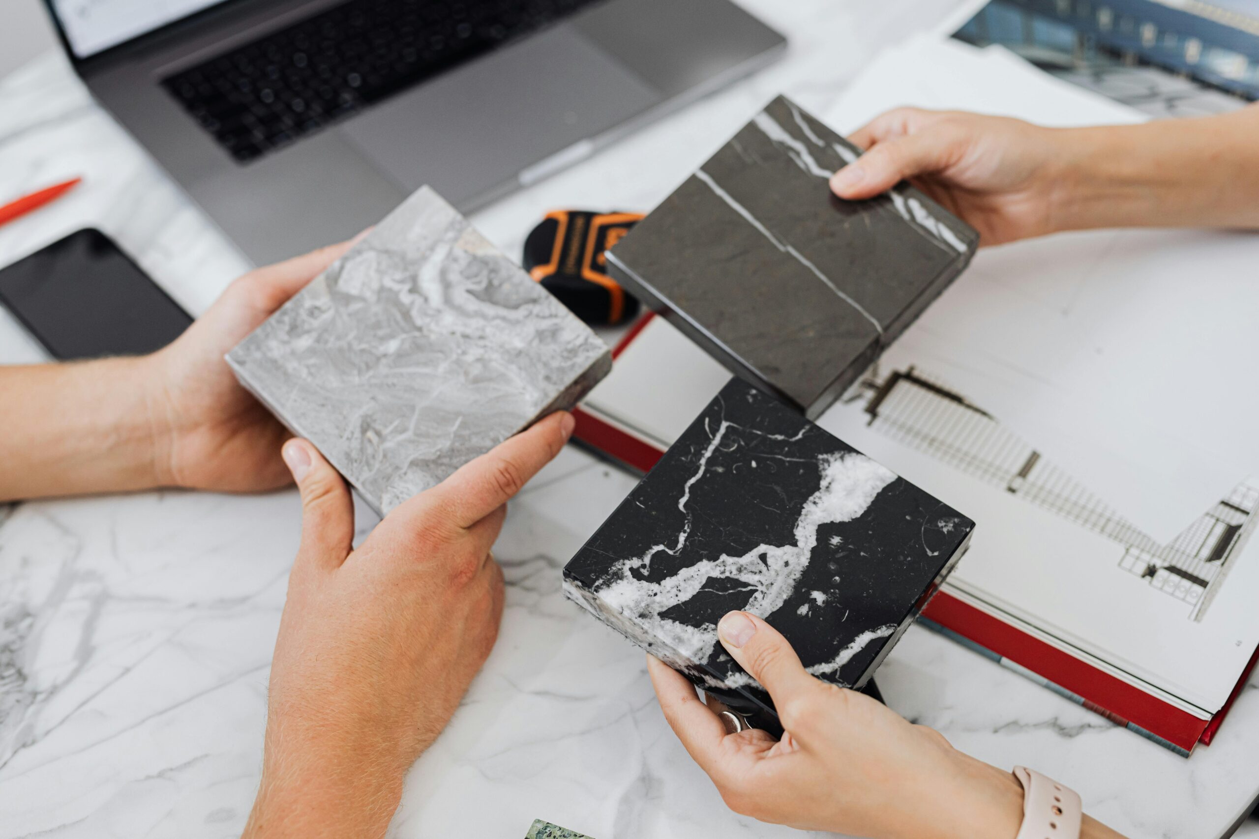 About Two architects selecting marble tile samples on a desk in an office setting.