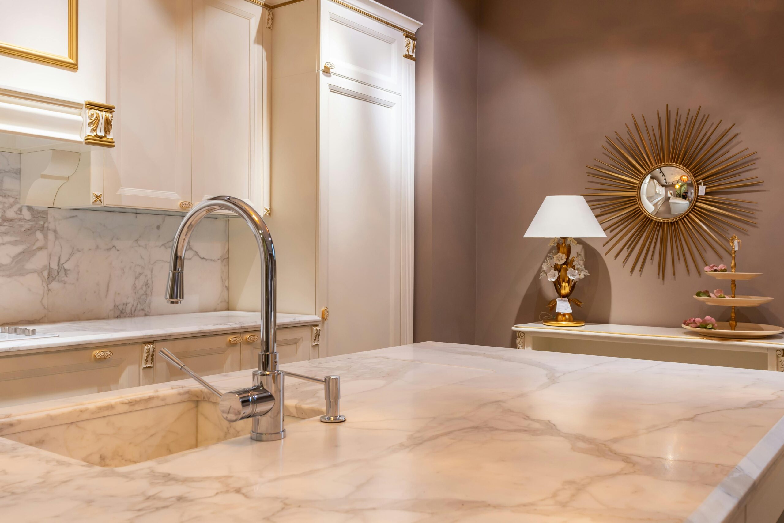 Products Sink with faucet on marble counter in modern stylish kitchen with white cabinets and glowing lamp near decorations in apartment